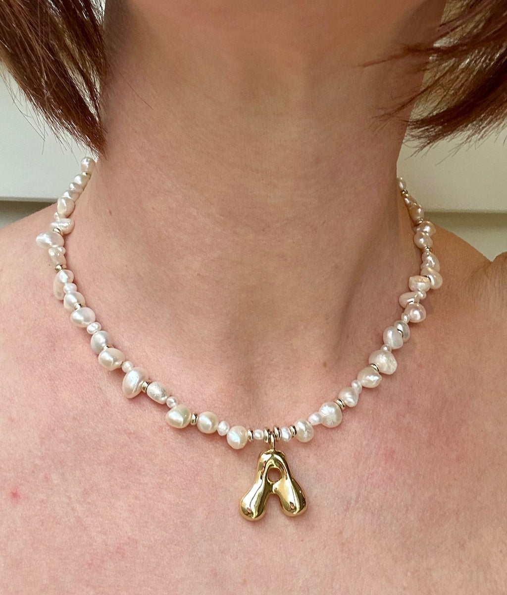 Pearl necklace with a gold charm worn by a person