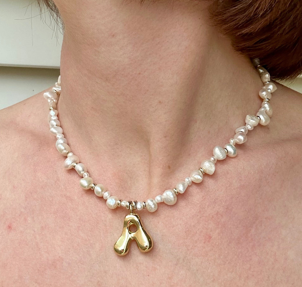 Pearl necklace with a gold pendant worn by a person