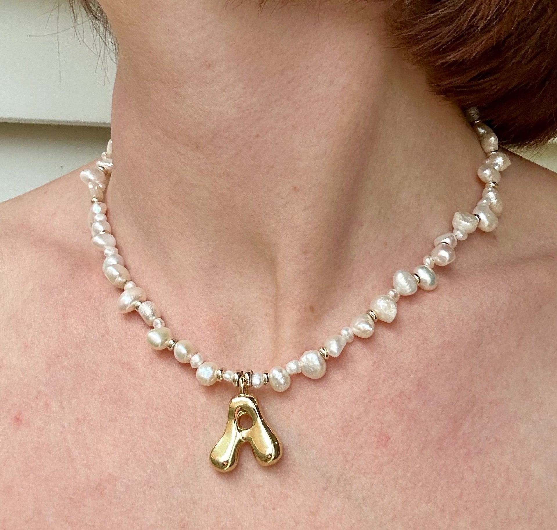 Pearl necklace with a gold pendant worn by a person