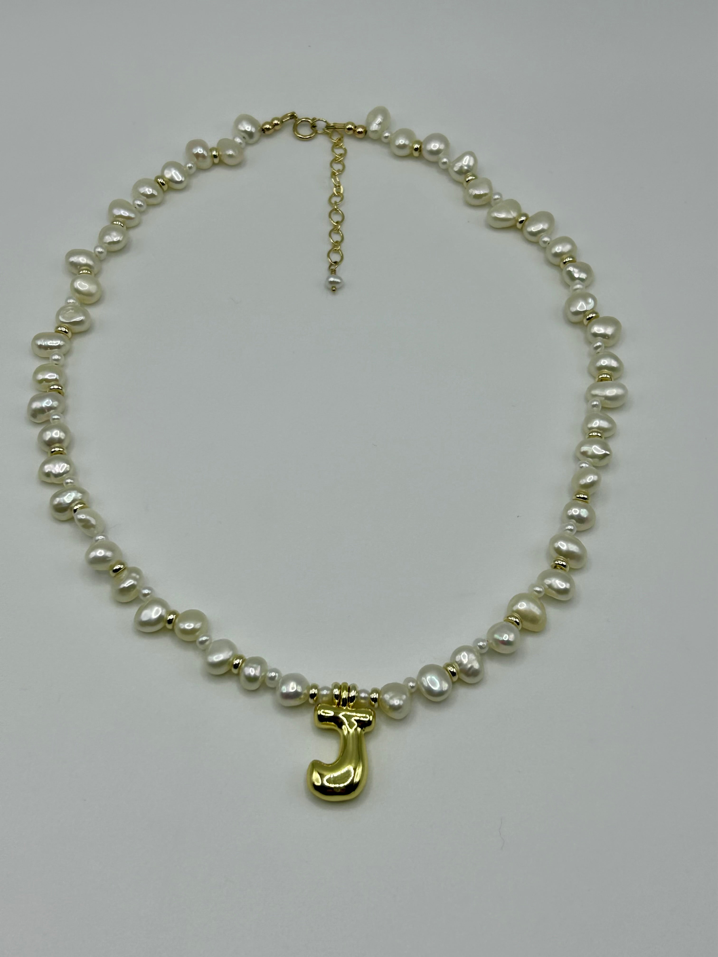 Pearl necklace with a gold letter 'J' charm on a light gray background